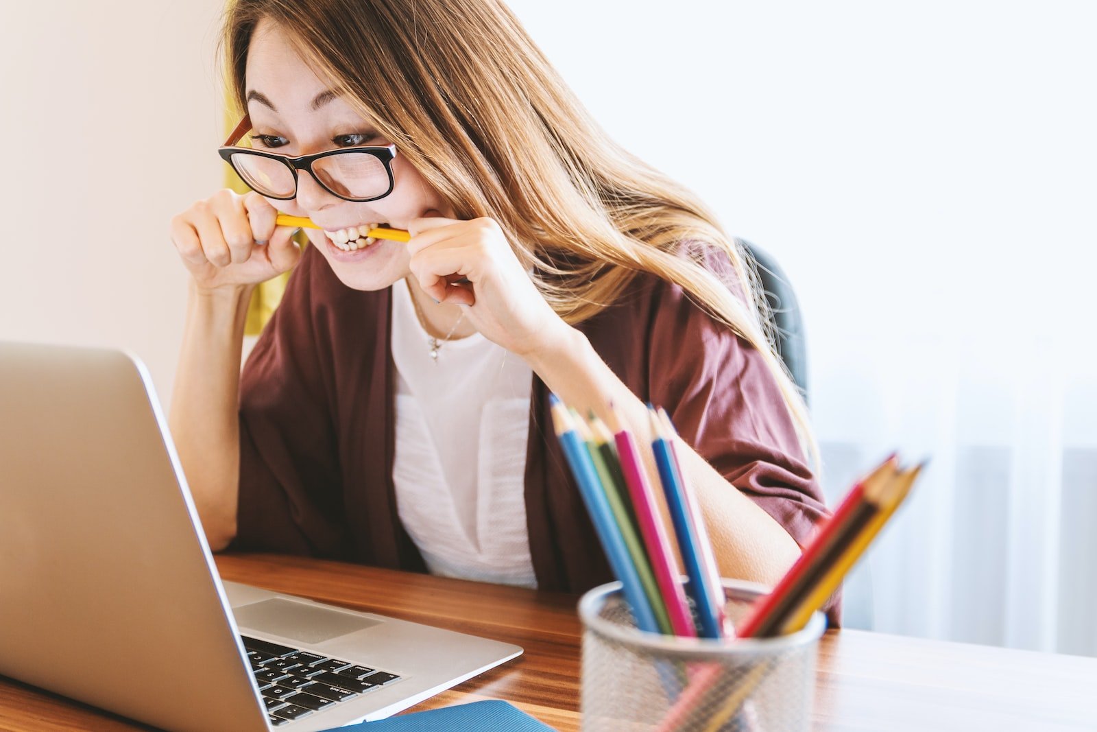 Triple S English training young lady biting her pencil at the computer