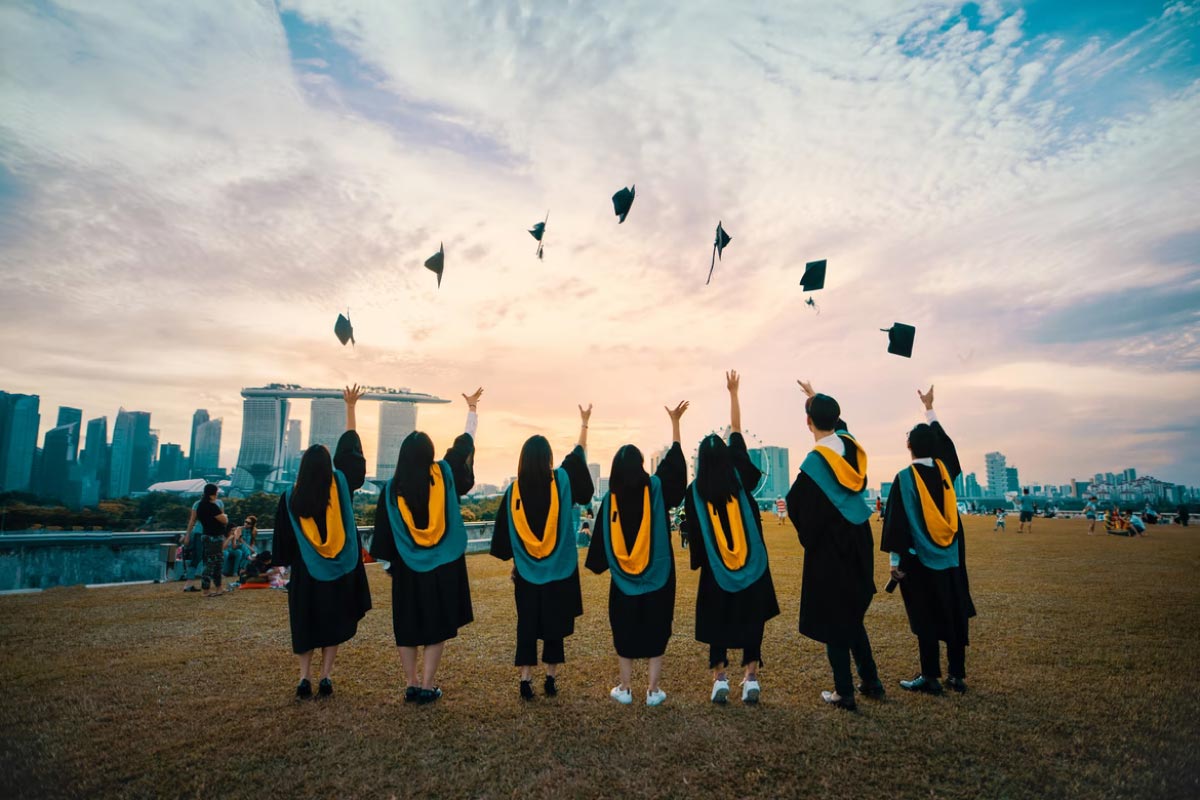 Triple S English Graduating students throwing mortar boards in the air.